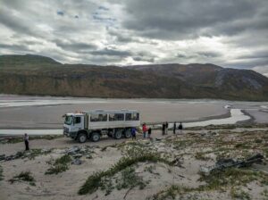 ACT_D1 8WD bus in greenlad nature in the dry riverbed with tourists around.
