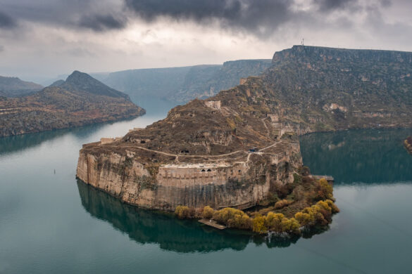 a castle carved in the rock wall with a Tigris river around it