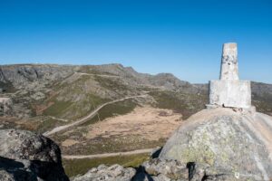 Portugal_Serra_da_Estrela-15 Winding road on the top of the mountain with a boulder with a small structure on top in the foreground