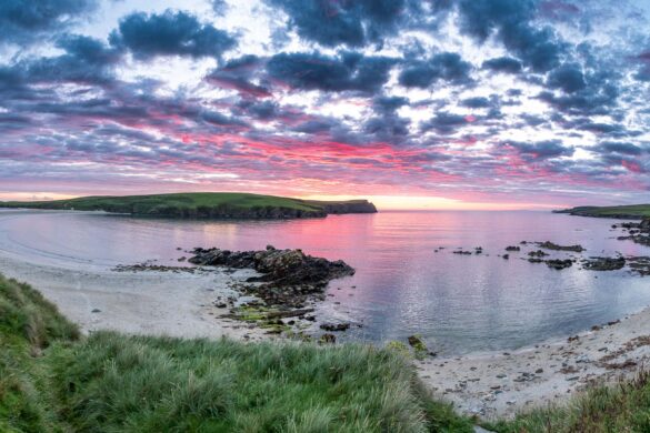 Beautiful bay in the scotland with sun setting and red clouds above the scenery