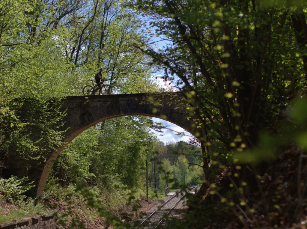 Cyclist riding over the bridge and railway below the arch