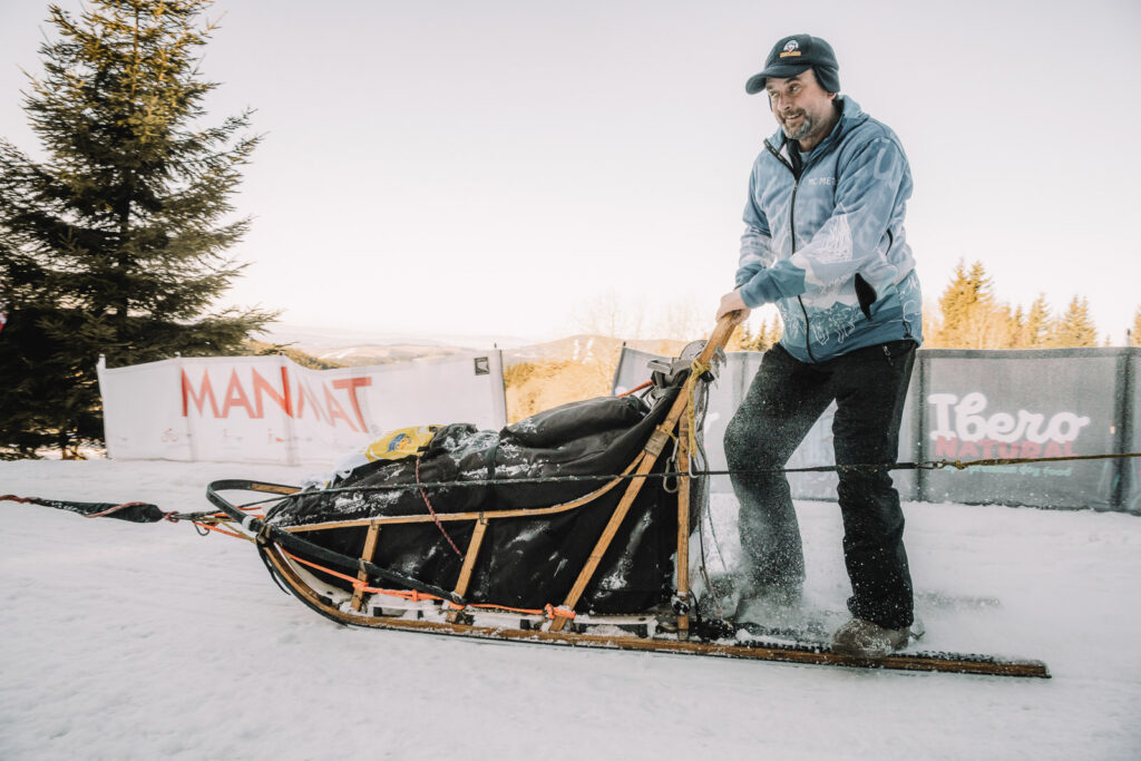 Happy musher on the sled dog race riding ont he sled
