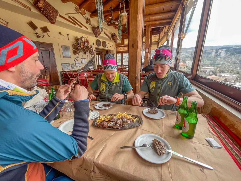 Tři lidé, kteří v taverně jedí řecké jídlo