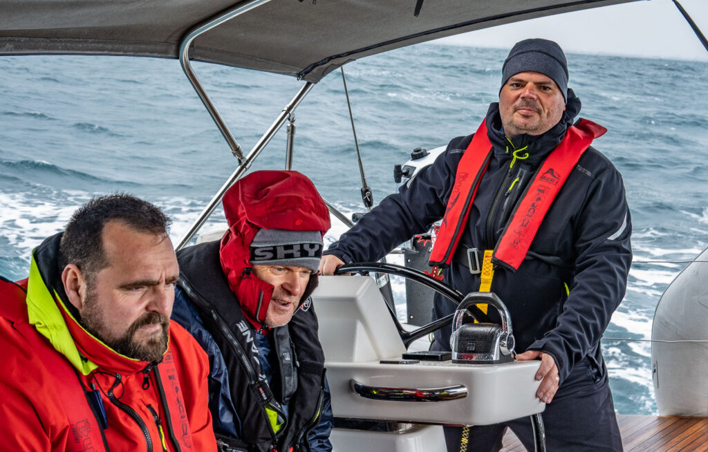 Guys sailing in a bad weather near Italian coast on a sailboat