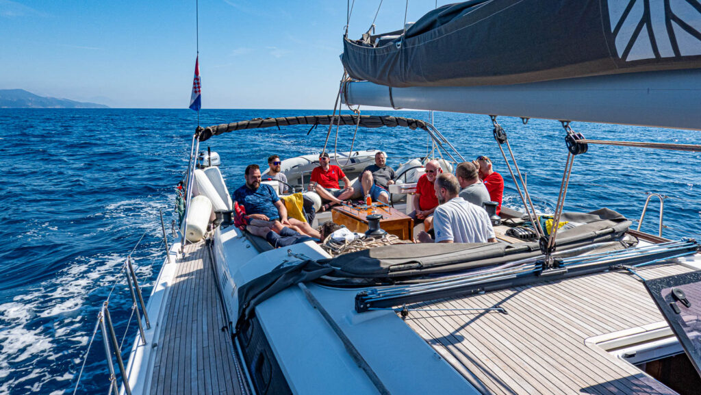 People sitting in the cockpit of the sailboat offshore